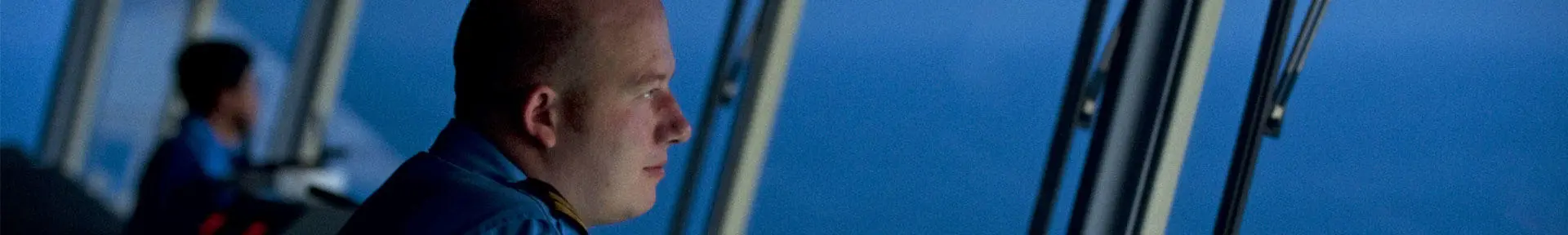 A senior deck officer looking out to sea from the bridge of a Maersk ship at night