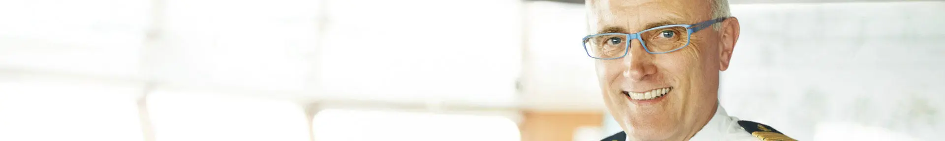 A smiling senior deck officer on the bridge of a ship