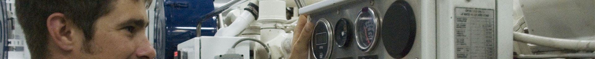 A superyacht engineer looking at dials and machinery in the engine room