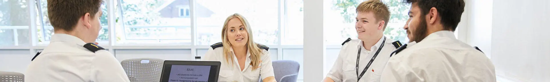 Four cadets sat around a table in the classroom with a laptop