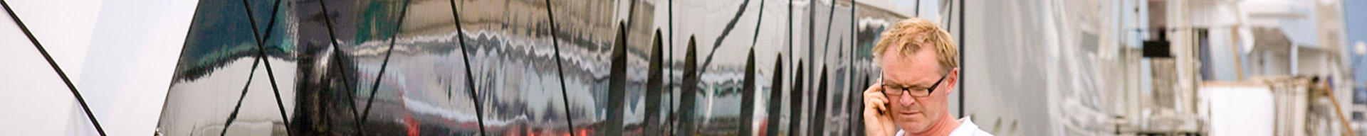 Man walking next to a superyacht talking on his mobile phone