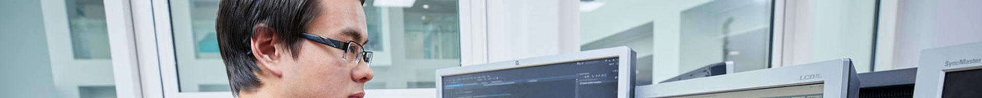 A student looking at a software programme on computer screens