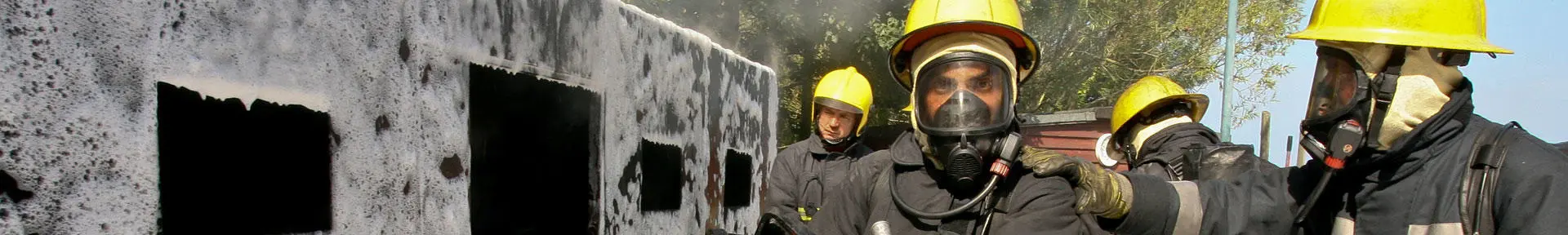 Fire fighting students next to a foam-covered structure where they've just put out a fire