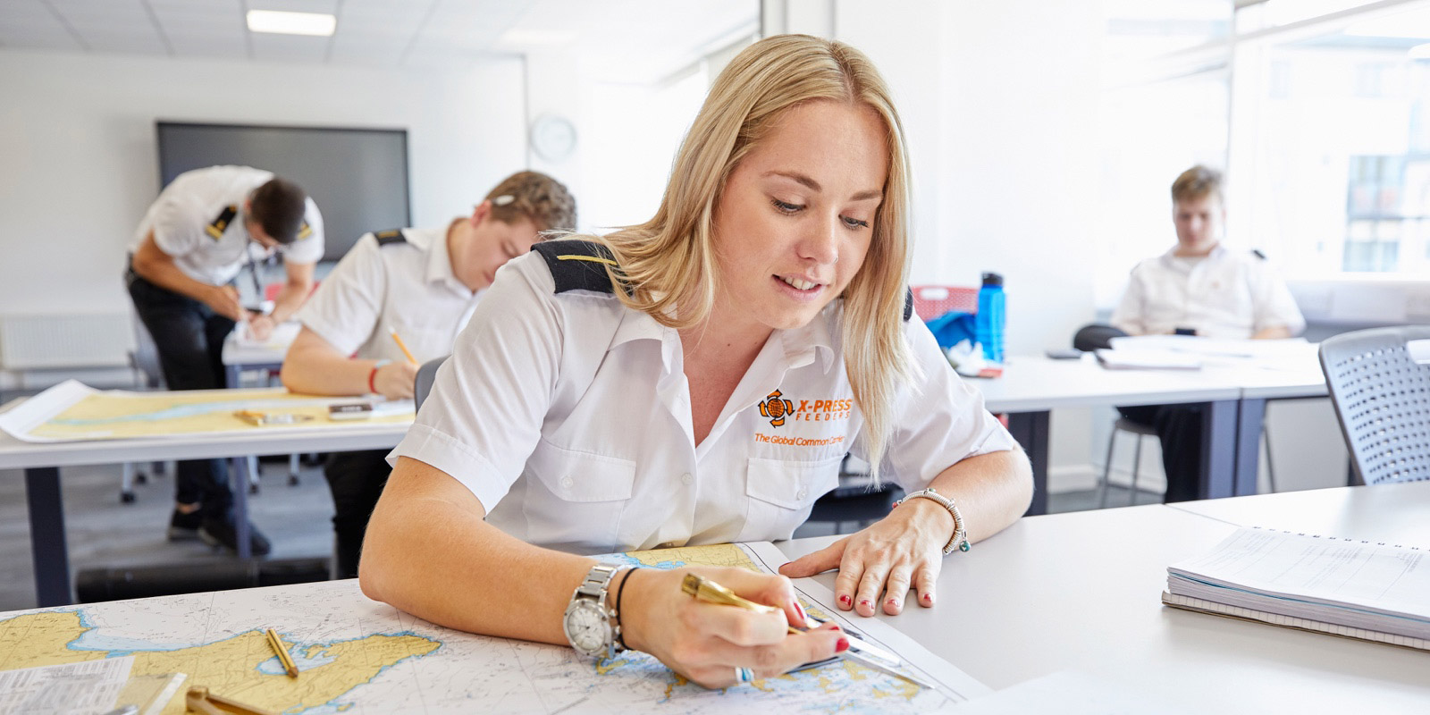 Female deck cadet doing chart work in the classroom