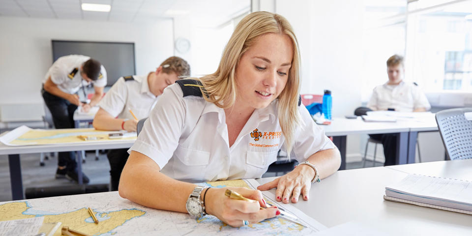 Female deck cadet doing chart work in the classroom