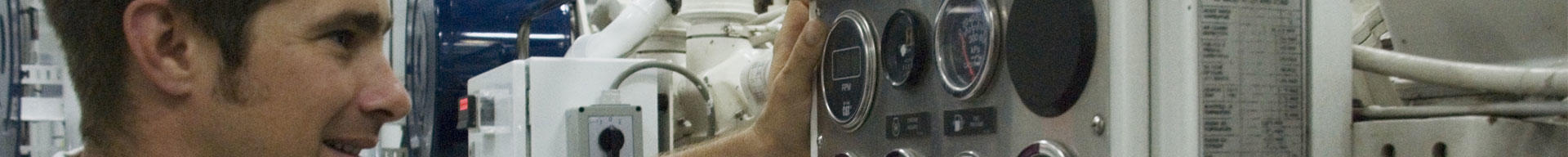 A superyacht engineer looking at dials and machinery in the engine room