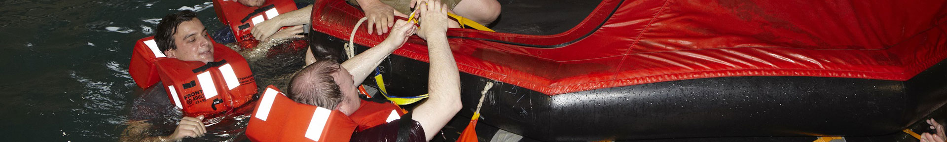 Students climbing into an inflatable life raft in the training pool