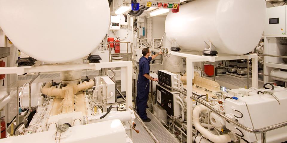 An engineer checking machinery in the engine room of a superyacht