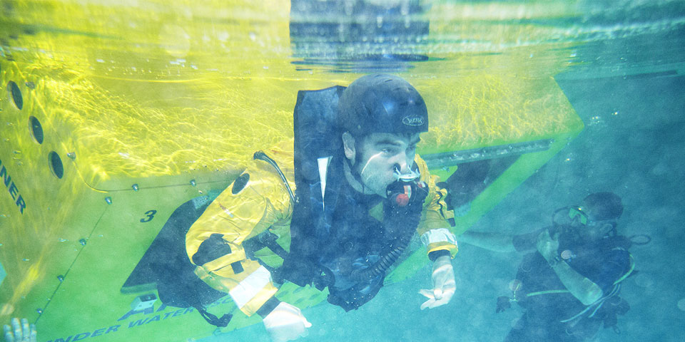 Underwater shot of a student emerging from the helicopter underwater escape trainer