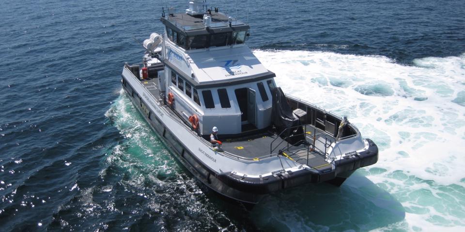 A small grey workboat with a crew on board attending to their job at sea
