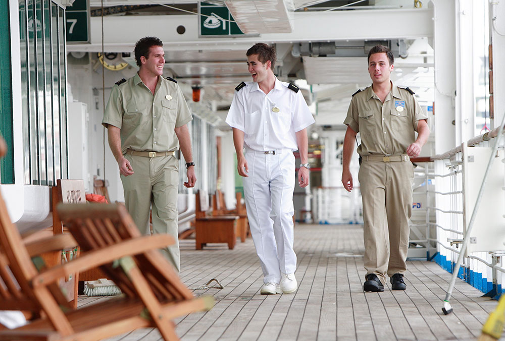 Carnival deck officers walking along the deck of a cruise ship