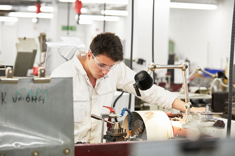 A male engineer cadet working at a station in the engineering workshops