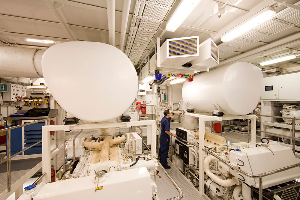 A superyacht engineer checking machinery in the engine room